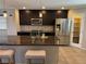 A kitchen featuring a granite countertop island, stainless steel appliances, and dark wood cabinets at 355 Gracious Way, Henderson, NV 89011