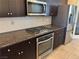 A view of a kitchen featuring stainless steel appliances, granite countertops and dark wood cabinetry at 355 Gracious Way, Henderson, NV 89011