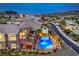 Aerial view of a beautiful property showcasing pool, balconies, lush landscaping, and city views in the background at 47 Strada Principale, Henderson, NV 89011