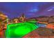 Beautiful pool with bright green lighting and hot tub surrounded by lush plants on a cloud-filled night at 47 Strada Principale, Henderson, NV 89011