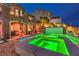 Outdoor oasis featuring a sparkling pool with attached hot tub, covered seating, and lush landscaping at 47 Strada Principale, Henderson, NV 89011