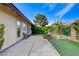 The backyard has a concrete patio, green turf, and is surrounded by mature trees and plants at 5541 Port Barrington Way, Las Vegas, NV 89130