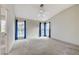 A spacious main bedroom featuring vaulted ceilings, three windows with blinds and drapes, and a ceiling fan at 5541 Port Barrington Way, Las Vegas, NV 89130