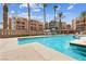 Community swimming pool with palm trees, lounge chairs, and multi-story condominium buildings at 59 E Agate Ave # 306, Las Vegas, NV 89123