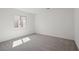 Minimalist bedroom with neutral carpet, white walls, and a large window offering plenty of natural light at 6760 Violet Cascade Ave, Las Vegas, NV 89156
