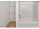 Shower and tub combo with white tiling, along with white wire shelving for storage at 7011 Overton St, Las Vegas, NV 89166