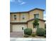 Tan two story home featuring a two car garage with a brick driveway and minimal landscaping at 7041 Fossil Rim St, North Las Vegas, NV 89084