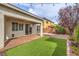 A lush backyard is showcased with artificial turf, brick pavers, and view of the two-story home at 7716 Twin Tails St, Las Vegas, NV 89149
