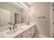 Bathroom with double sinks, white cabinets, and large mirror at 7716 Twin Tails St, Las Vegas, NV 89149