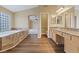 Bright bathroom featuring wood floors, a soaking tub with tile surround, double vanity with granite counters at 7808 Brook Valley Dr, Las Vegas, NV 89123