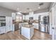 Well-lit kitchen features stainless steel appliances, white cabinetry, a granite island, and wood-style flooring at 7898 Red Rock Ridge Ave, Las Vegas, NV 89179