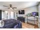 A stylish bedroom featuring a fan, TV, dark furniture, and wood-style floors at 7898 Red Rock Ridge Ave, Las Vegas, NV 89179