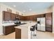 Modern kitchen with dark wood cabinets, stainless steel appliances, quartz countertops, and breakfast bar seating at 8141 Guava Nectar Ave, Las Vegas, NV 89131