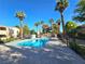 Community pool surrounded by palm trees and lush greenery on a sunny day at 8452 Boseck Dr # 216, Las Vegas, NV 89145