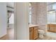 Bathroom featuring a wooden vanity and sink with wallpapered walls and access to another room at 931 Temple View Dr, Las Vegas, NV 89110