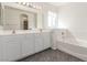 Bathroom featuring double sinks, a large mirror, and a separate bathtub at 9339 Bondeno St, Las Vegas, NV 89123