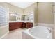 Bathroom featuring a soaking tub, dual sinks, and dark wooden cabinets at 1111 Casa Palermo Cir, Henderson, NV 89011