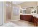 Well-lit bathroom with dual sinks, dark cabinets, and a walk-in shower at 1111 Casa Palermo Cir, Henderson, NV 89011