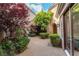 Secluded courtyard with mature trees, a decorative gravel surface, and an arched walkway at 11359 Winter Cottage Pl, Las Vegas, NV 89135