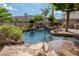 Luxurious backyard features a rock waterfall, lagoon-style pool, lush landscaping, and a built-in barbecue area at 11359 Winter Cottage Pl, Las Vegas, NV 89135