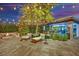 Luxurious backyard patio with outdoor kitchen, fire pit, and lounge area illuminated by string lights at 2208 Point Rock Ln, Las Vegas, NV 89134