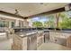Outdoor kitchen with stone counters, built-in stainless appliances and bar seating at 2208 Point Rock Ln, Las Vegas, NV 89134