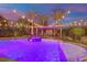 A luxurious pool with a spa featuring waterfalls and illuminated lighting, set against palm trees and a twilight sky at 2208 Point Rock Ln, Las Vegas, NV 89134