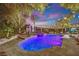 Resort-style pool and spa with waterfall feature, surrounded by lush landscaping and ambient lighting at 2208 Point Rock Ln, Las Vegas, NV 89134