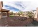 Large backyard with covered patio, rock feature, and desert landscaping at 2532 Bechamel Pl, Henderson, NV 89044