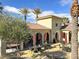 Outdoor patio with tables and umbrellas, adjacent to a beige building with tile roof, and greenery at 2555 Hampton Rd # 10104, Henderson, NV 89052