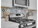 Close-up of a modern kitchen featuring stainless steel appliances and decorative tile backsplash at 272 Mount Steele Ave, Henderson, NV 89015