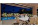 Nighttime view of outdoor patio table, chairs and sparkling blue pool with lush landscaping at 5416 Alabaster Ct, Las Vegas, NV 89149