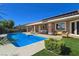 Wide angle of backyard featuring sparkling pool, covered patio and neatly manicured artificial lawn at 5416 Alabaster Ct, Las Vegas, NV 89149