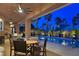 Covered patio with ceiling fans and dining area overlooks a sparkling pool and lush landscaping at twilight at 5416 Alabaster Ct, Las Vegas, NV 89149