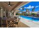 Inviting covered outdoor patio area with a ceiling fan, comfortable seating, and sparkling blue pool at 5416 Alabaster Ct, Las Vegas, NV 89149