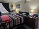 Comfortable bedroom with a black headboard, complimented with red and black striped bedspread and dark wood dresser at 5419 Centurion Ct # 102, Las Vegas, NV 89122