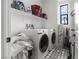 Functional laundry room featuring modern appliances, storage, and unique star patterned floor at 6142 W Levi Ave, Las Vegas, NV 89141