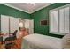 Cozy bedroom with green textured walls, shutters, and an open view to the living area at 708 Canterbury Cross Pl, Las Vegas, NV 89144