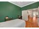 Well-lit bedroom featuring green walls, hardwood floors, and an open door to the living area at 708 Canterbury Cross Pl, Las Vegas, NV 89144