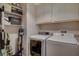 Well-organized laundry room with white washer, dryer, and built-in shelving at 708 Canterbury Cross Pl, Las Vegas, NV 89144