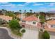 Expansive community view featuring a two-story home with a two-car garage, lush landscaping, and a terracotta roof at 7632 Spruce Run Ct, Las Vegas, NV 89128
