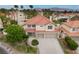 Expansive community view featuring a two-story home with a two-car garage, lush landscaping, and a terracotta roof at 7632 Spruce Run Ct, Las Vegas, NV 89128
