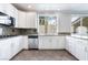 Modern kitchen boasts granite countertops, white cabinets, stainless steel appliances, and tile flooring at 7632 Spruce Run Ct, Las Vegas, NV 89128