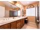 Bathroom boasts dual sinks with wood cabinets, marble countertop, and a shower with a glass door at 8180 Loma Del Ray St, Las Vegas, NV 89131