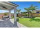 Well-manicured backyard with a covered patio, a swing bench, verdant lawn, and lush landscaping at 8349 Pollenzo Ave, Las Vegas, NV 89178