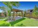 Serene backyard with a wooden pergola surrounded by green space and trees at 8349 Pollenzo Ave, Las Vegas, NV 89178