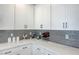 Kitchen with white cabinets, gray backsplash, marble counters and decorative accents at 8349 Pollenzo Ave, Las Vegas, NV 89178