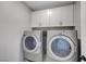 Bright laundry room with new washer and dryer, as well as upper cabinets at 8349 Pollenzo Ave, Las Vegas, NV 89178