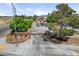 View of the property entrance with a decorative gate, mature landscaping, and ample parking at 8970 W Lone Mountain Rd, Las Vegas, NV 89129