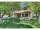 Charming two-story home with a stone facade porch, lush green lawn, and mature trees providing shade at 8970 W Lone Mountain Rd, Las Vegas, NV 89129